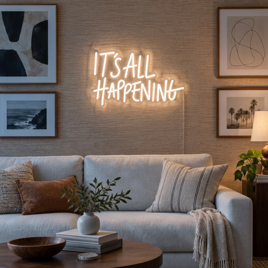 White It's All Happening LED neon sign above an ivory sofa on a gallery wall at dusk.