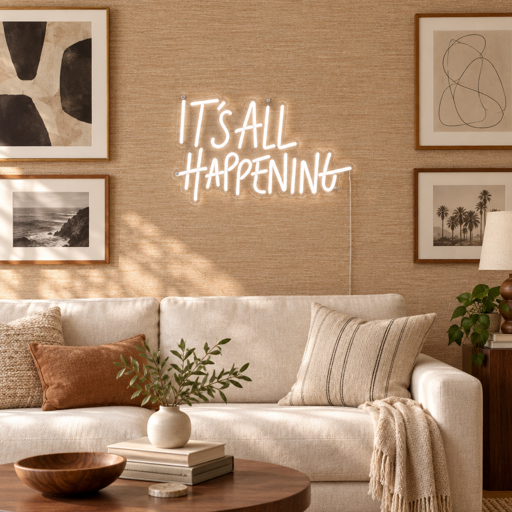 White It’s All Happening LED neon sign displayed among framed artwork on a gallery wall in a modern lounge.